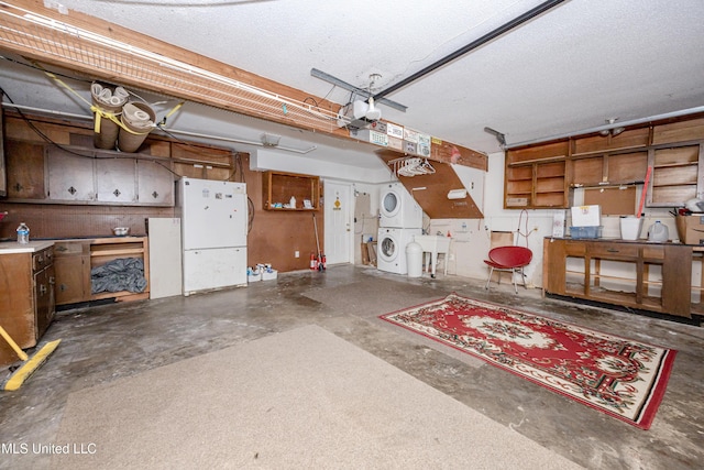 garage with a garage door opener, stacked washer / drying machine, freestanding refrigerator, and a sink