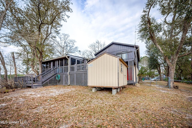 back of property with a sunroom, fence, and stairway