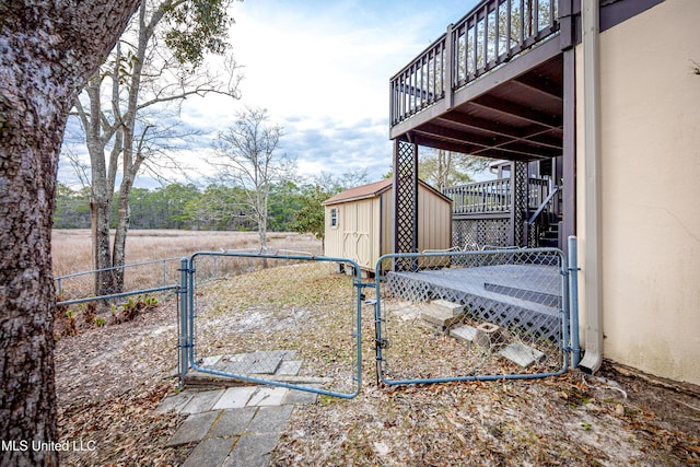 view of yard with a gate, fence, a deck, a shed, and an outdoor structure