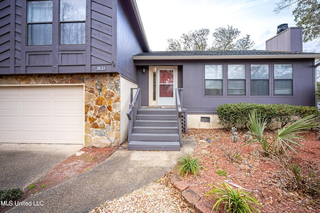 tri-level home with a garage, crawl space, a chimney, and concrete driveway