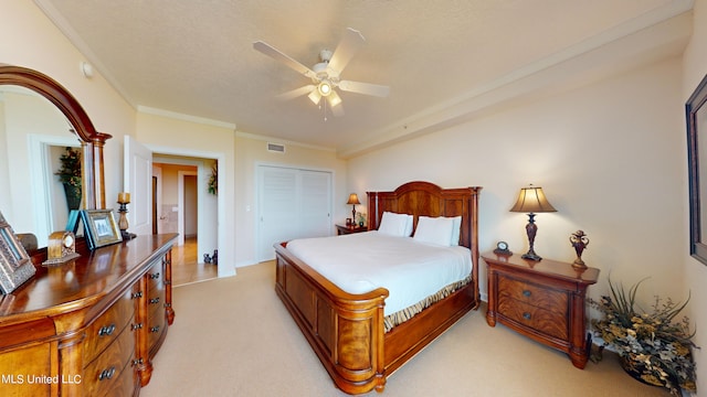 carpeted bedroom featuring a closet, ceiling fan, ornamental molding, and a textured ceiling