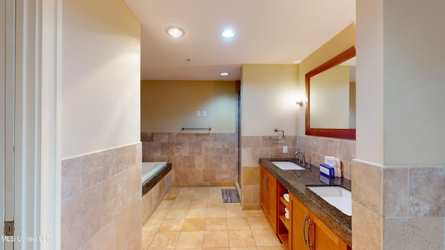 bathroom with vanity, a tub, tile patterned floors, and tile walls