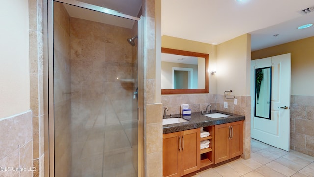 bathroom featuring vanity, walk in shower, tile patterned floors, and tile walls