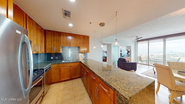 2060 Beach Blvd Unit 701, Biloxi, MS 39531 - kitchen featuring stainless steel appliances, a sink, brown cabinetry, a peninsula, and light tile patterned flooring