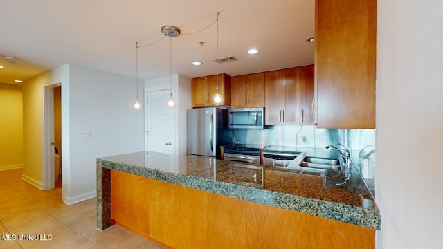 2060 Beach Blvd Unit 701, Biloxi, MS 39531 - kitchen with stainless steel appliances, brown cabinetry, pendant lighting, dark stone counters, and light tile patterned floors