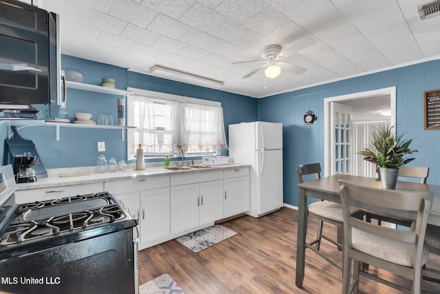 1264 28th St, Gulfport, MS 39501 - kitchen featuring freestanding refrigerator, gas range, a sink, a ceiling fan, and white cabinets