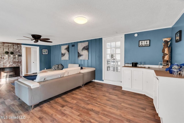 1264 28th St, Gulfport, MS 39501 - living area with a textured ceiling, wood finished floors, a fireplace, a ceiling fan, and crown molding