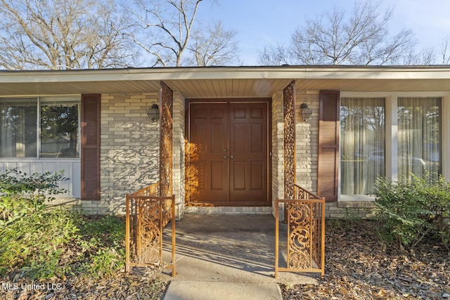 view of exterior entry with board and batten siding and brick siding