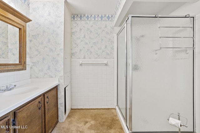 bathroom with carpet, tile walls, a shower stall, vanity, and wallpapered walls