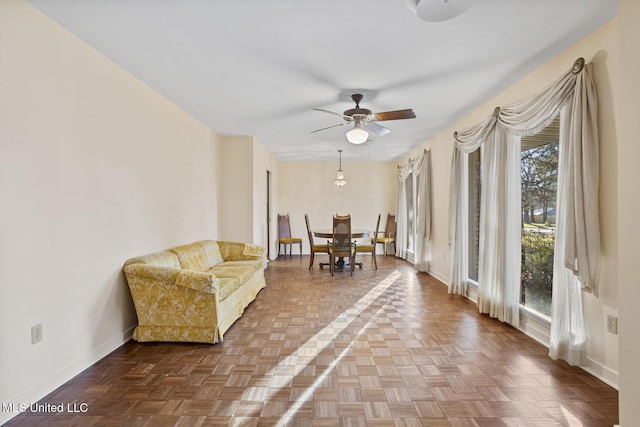 sitting room with a ceiling fan and baseboards