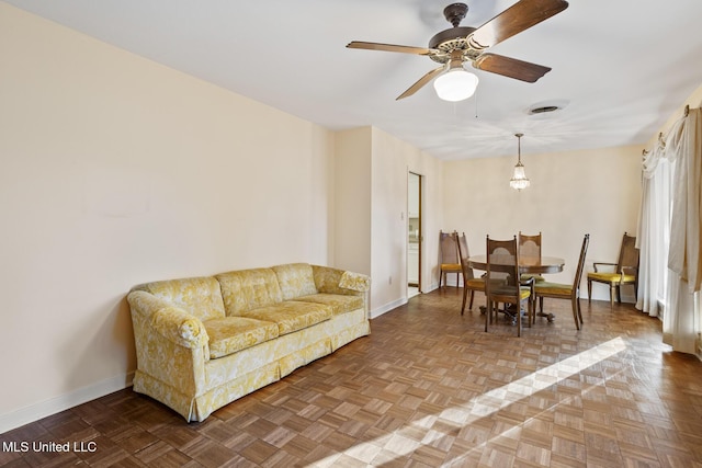 living area featuring visible vents, ceiling fan, and baseboards