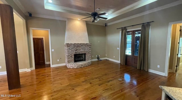 unfurnished living room with wood-type flooring, a fireplace, and a raised ceiling