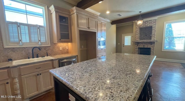 kitchen featuring a kitchen island, hanging light fixtures, sink, crown molding, and a brick fireplace