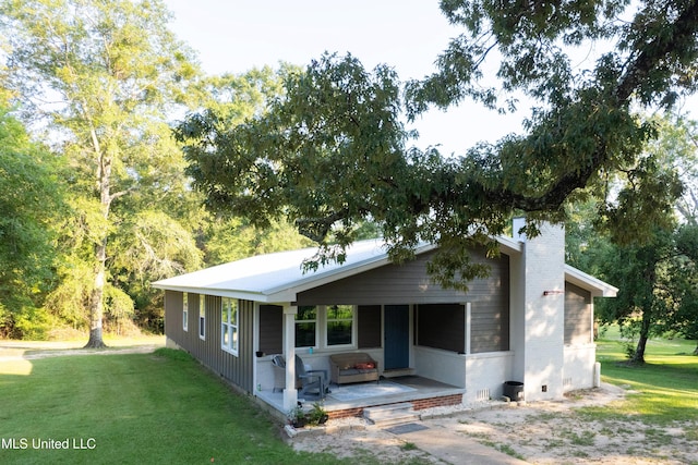 view of front of house featuring a chimney, a patio, and a front yard