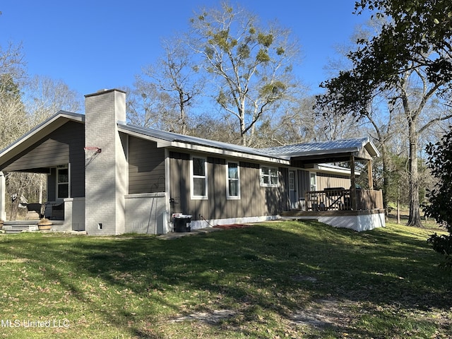 back of house with a deck, a lawn, and a chimney