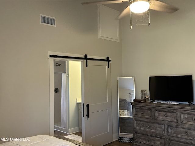 bedroom with a barn door, visible vents, and a ceiling fan