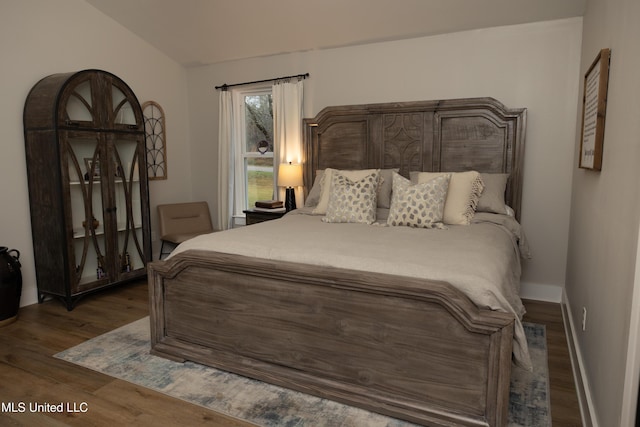 bedroom featuring baseboards, vaulted ceiling, and wood finished floors