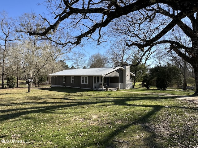 view of front of home featuring covered porch, metal roof, a chimney, and a front yard