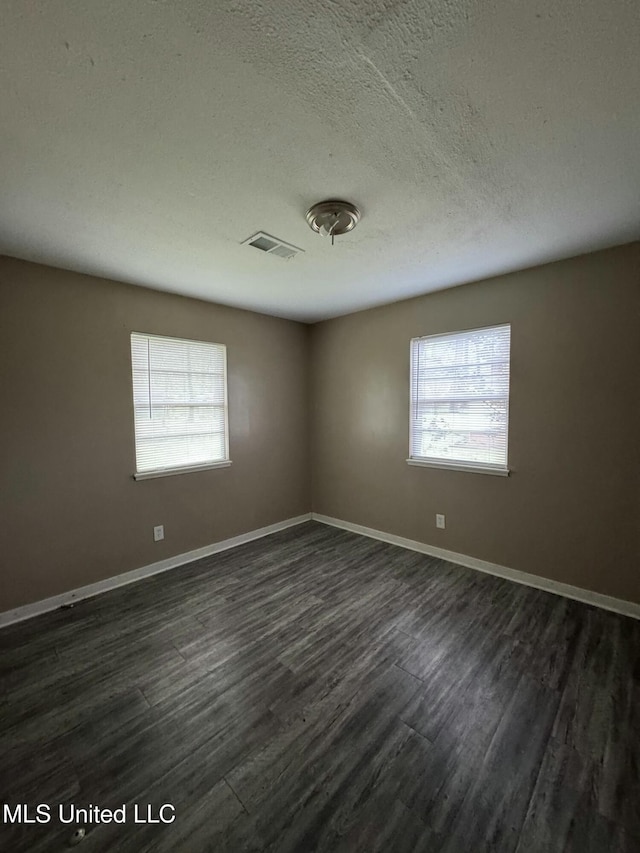 spare room with baseboards, dark wood-style floors, and a healthy amount of sunlight