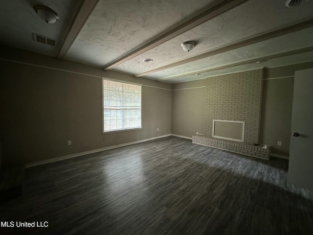 unfurnished room featuring dark wood-type flooring, baseboards, visible vents, and beam ceiling