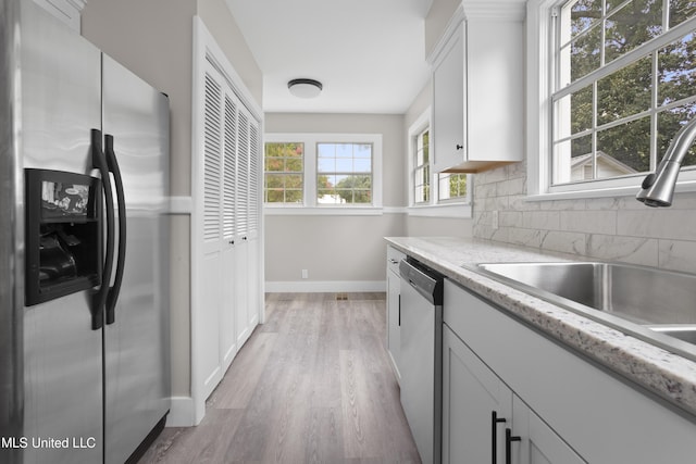 157 Saint Charles Ave, Biloxi, MS 39530 - kitchen with appliances with stainless steel finishes, light wood-style flooring, tasteful backsplash, white cabinetry, and light stone countertops