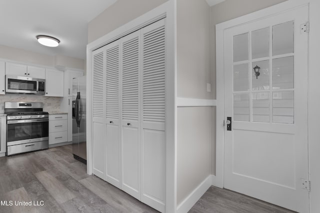 157 Saint Charles Ave, Biloxi, MS 39530 - kitchen with stainless steel appliances, light wood-style floors, backsplash, white cabinets, and light stone counters