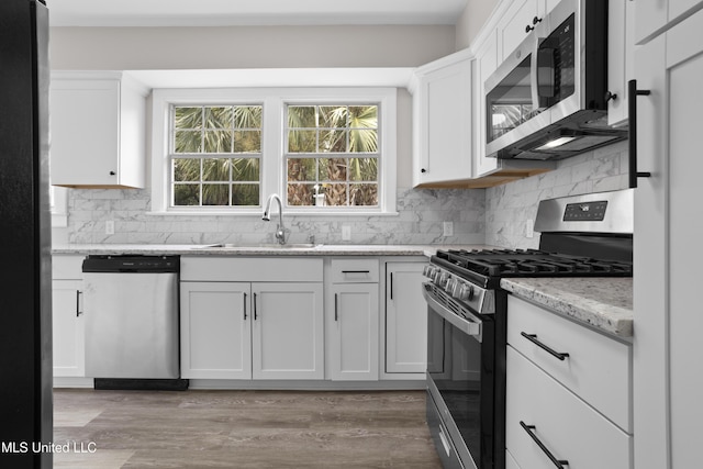 157 Saint Charles Ave, Biloxi, MS 39530 - kitchen with appliances with stainless steel finishes, white cabinetry, light stone countertops, decorative backsplash, and healthy amount of natural light