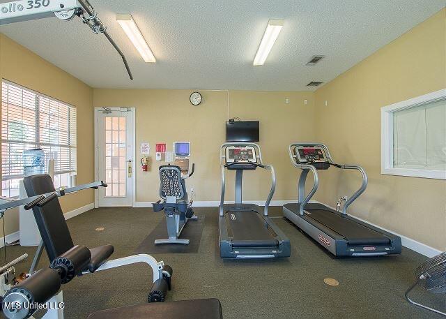 exercise room with visible vents, a textured ceiling, and baseboards