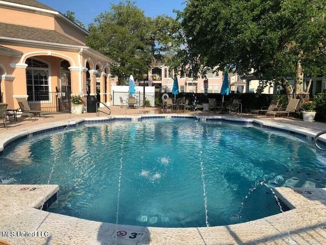 community pool featuring fence and a patio