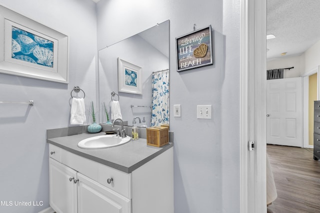 full bath with a textured ceiling, wood finished floors, and vanity