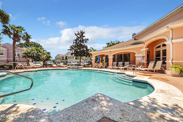 community pool with a patio and fence