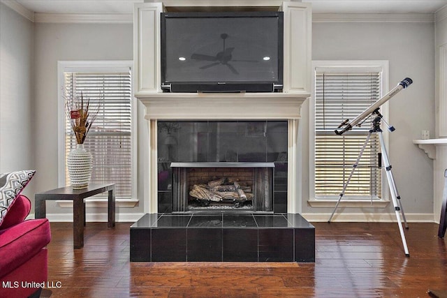 interior details featuring hardwood / wood-style flooring, a tile fireplace, ceiling fan, and crown molding