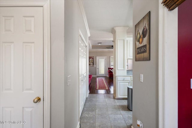 corridor featuring ornate columns, ornamental molding, and light tile patterned floors