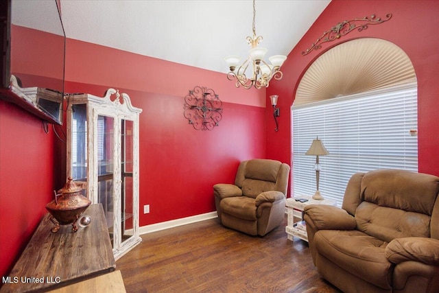 sitting room with lofted ceiling, dark hardwood / wood-style floors, and an inviting chandelier