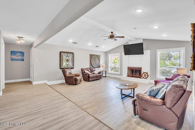 living room featuring lofted ceiling with beams, plenty of natural light, light wood-style flooring, and a fireplace