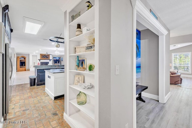 hallway featuring baseboards and brick floor