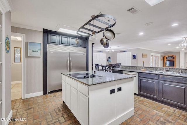 kitchen featuring visible vents, appliances with stainless steel finishes, a kitchen island, and brick floor