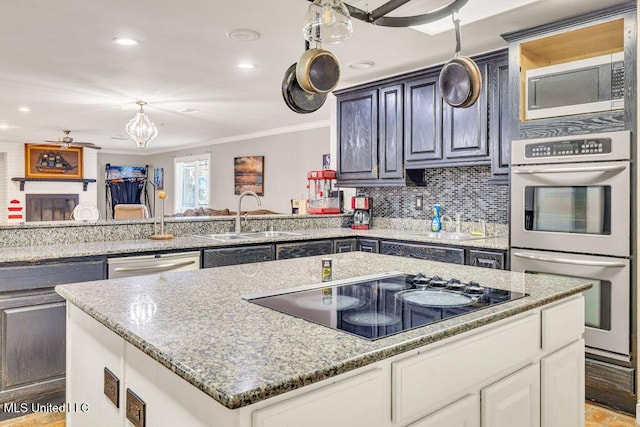 kitchen featuring light stone counters, a sink, decorative backsplash, ornamental molding, and stainless steel appliances