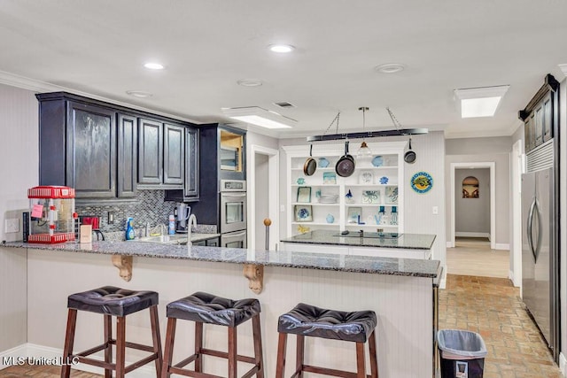 kitchen with backsplash, a breakfast bar area, a peninsula, brick floor, and stainless steel appliances