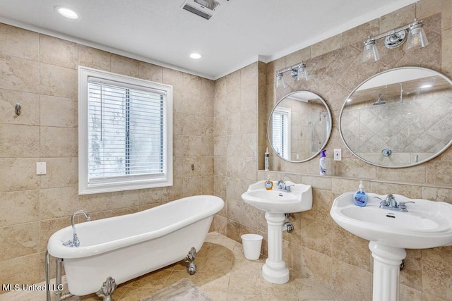 bathroom featuring tile walls, recessed lighting, visible vents, and a freestanding bath