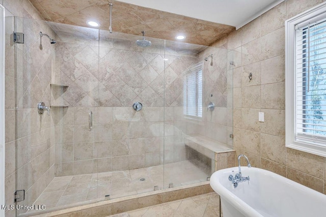 bathroom with recessed lighting, a stall shower, a freestanding bath, and tile walls