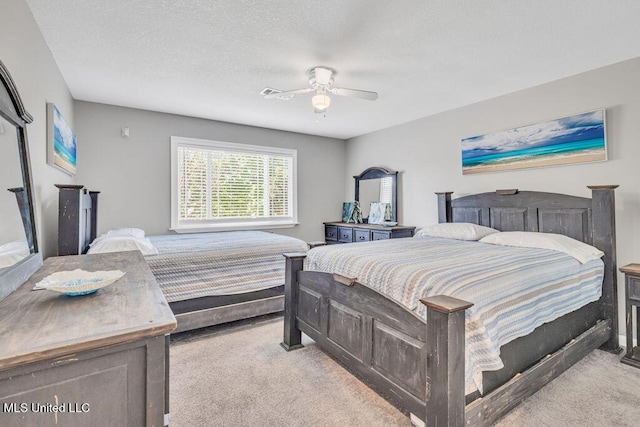 carpeted bedroom featuring ceiling fan and a textured ceiling