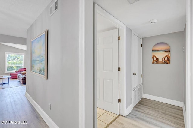 hallway with light wood-type flooring, visible vents, and baseboards