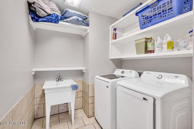 laundry room with washing machine and dryer, laundry area, wainscoting, light tile patterned flooring, and a textured ceiling