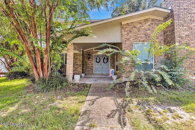 entrance to property with brick siding and a porch