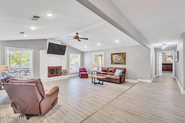 living area featuring visible vents, plenty of natural light, vaulted ceiling with beams, and light wood finished floors