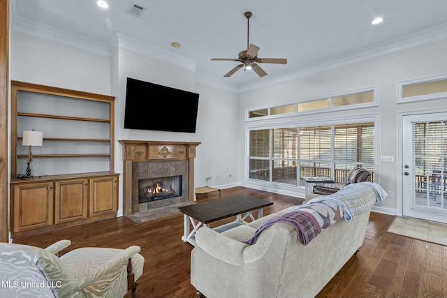 living room featuring crown molding, ceiling fan, a fireplace, and dark hardwood / wood-style flooring