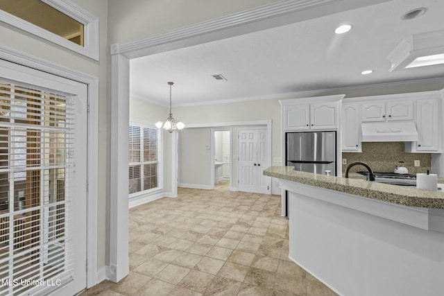 kitchen with premium range hood, stainless steel refrigerator, tasteful backsplash, white cabinetry, and crown molding