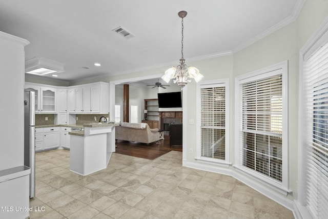 kitchen with hanging light fixtures, white cabinetry, crown molding, and kitchen peninsula