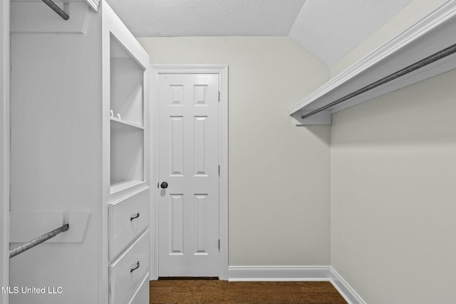 walk in closet featuring dark hardwood / wood-style floors and vaulted ceiling